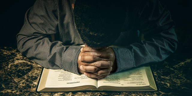 Man praying to God on an open Bible